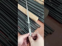 Een man toont een klein onderdeel gemaakt van koolstofstaalpijp